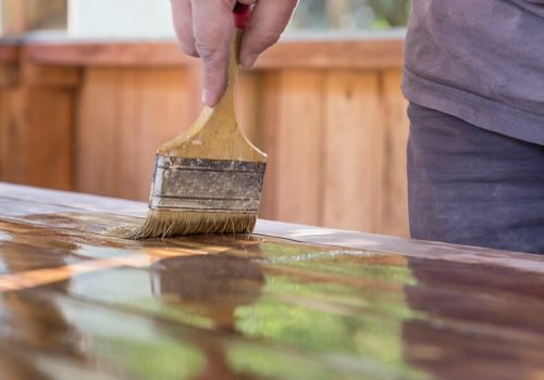 male hand with brush varnishes wooden planks